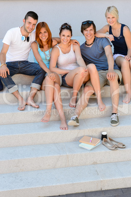Happy college students sitting on stairs summer