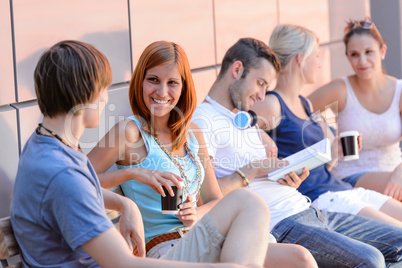 College students sitting by modern wall outside
