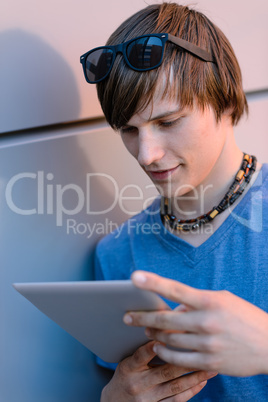 Student boy with tablet leaning against wall