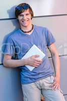 Smiling student boy leaning against modern wall