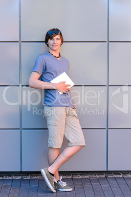 Confident college student boy with tablet standing