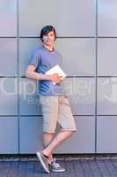 Confident college student boy with tablet standing