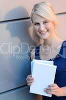 Smiling blond student girl with books outside