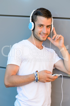 Smiling student boy with headphones against wall