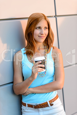 Thoughtful student girl standing by modern wall