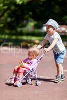 Boy pushing sister in a stroller