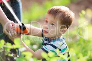Little boy playing with a jet of water in a garden