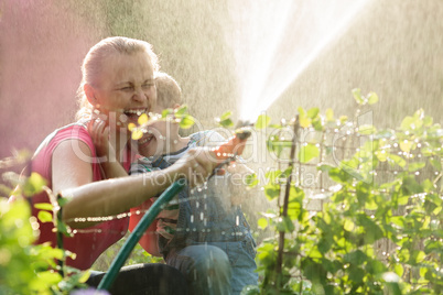 Laughing mother and son playing with a sprinkler