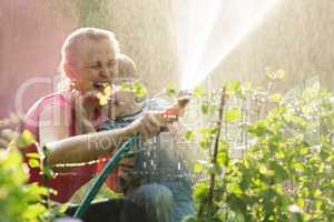 Laughing mother and son playing with a sprinkler