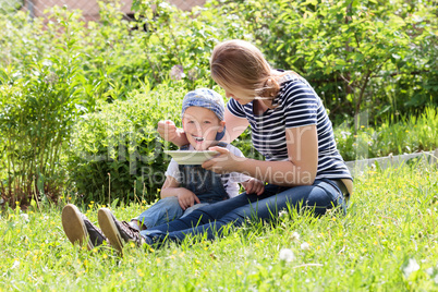 Mother feeding her son on the grass