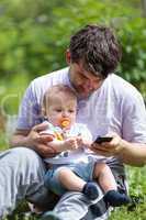 Father using a mobile with a baby on his lap