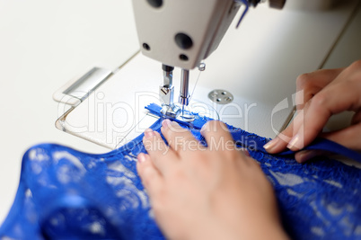 Hands of a woman sewing blue fabric