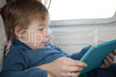 Small boy looking at a tablet in an airplane