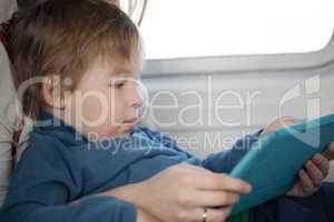 Small boy looking at a tablet in an airplane
