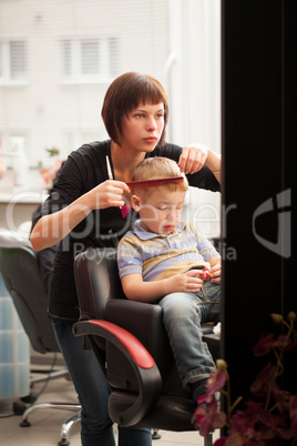 Little boy getting a haircut from hairdresser
