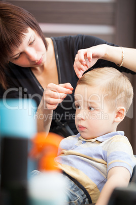 Hairdresser finishing boys haircut with hair setting