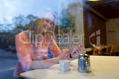 Young woman using a mobile phone in a cafeteria