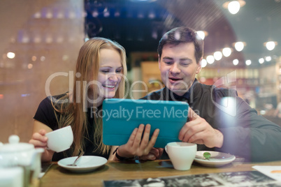 Young people drinking coffee and looking on pad