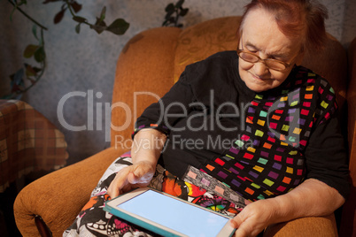 Elderly lady sitting in an chair using a tablet