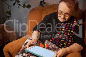 Elderly lady sitting in an chair using a tablet