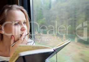 Young woman on a train writing notes