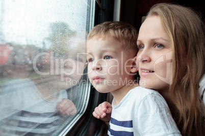 Mother and son looking through a train window