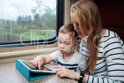 Son and his mom with tablet PC in the train