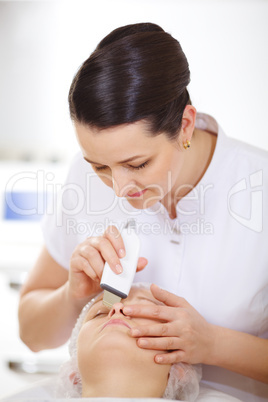 Cosmetician making ultrasonic face cleaning