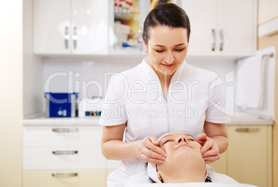 Professional beautician during the seance of facial massage