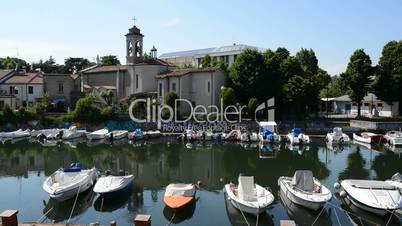 The water channel with parked motor boats and Catholic church, Rimini, Italy