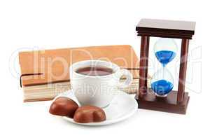 hourglass tea cup and a book on a white background