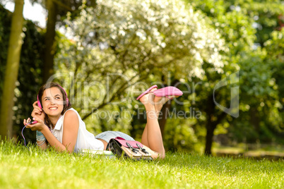 Cheerful student girl lying park listen music