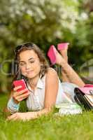 Teenage girl with mobile phone lying grass