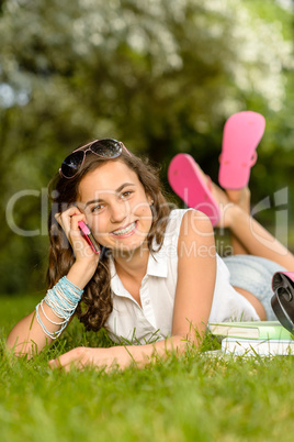 Cheerful student girl lying grass calling phone