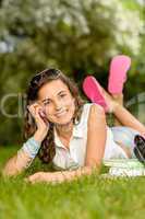 Cheerful student girl lying grass calling phone