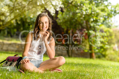 Smiling student girl sitting grass summer park