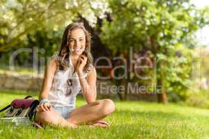 Smiling student girl sitting grass summer park