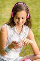 Teenage girl with headphones sitting on grass
