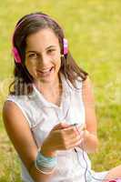 Laughing teenage girl listen music sitting grass