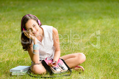 Student girl with headphones sitting on grass