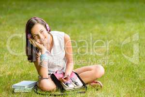 Student girl with headphones sitting on grass