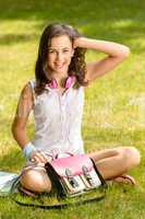 Cheerful student girl sitting on grass summer