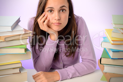 Bored student girl sitting between stack books