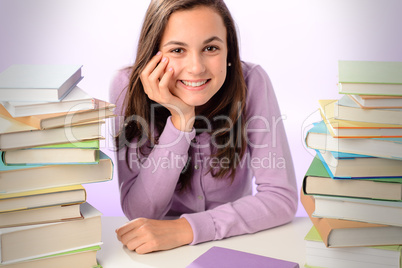 Smiling student girl between stacks of books