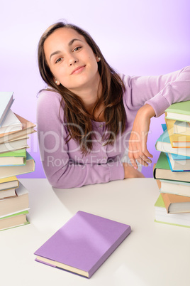 Confident student girl between stacks of books