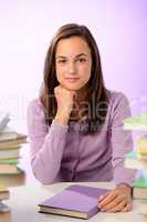 Confident student girl between stacks of books
