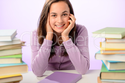 Smiling student girl between piles of books