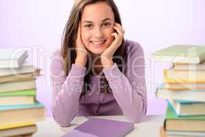 Smiling student girl between piles of books