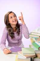 Smiling student girl pointing up purple background