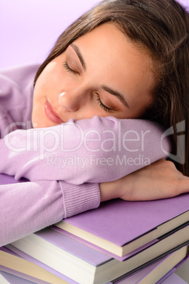 Tired student girl sleeping on purple books